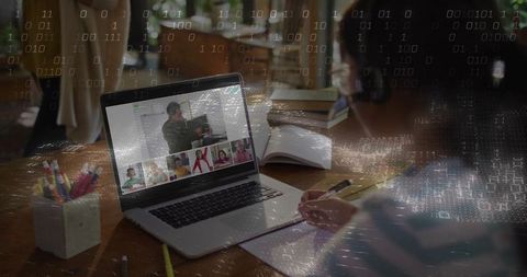 Schoolchild wearing headset joining virtual classroom at home using laptop and notebook
