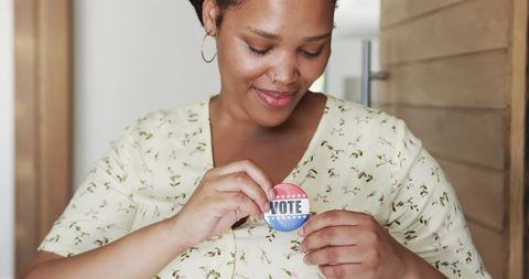 Young woman promoting civic engagement with voting badge at home