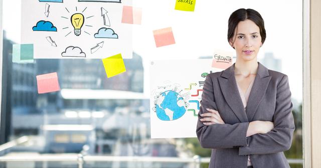 Businesswoman standing with arms crossed in front of a glass wall covered with sticky notes and drawings. Ideal for use in business, corporate, and professional contexts, such as websites, presentations, and marketing materials highlighting leadership, strategy, and innovation.