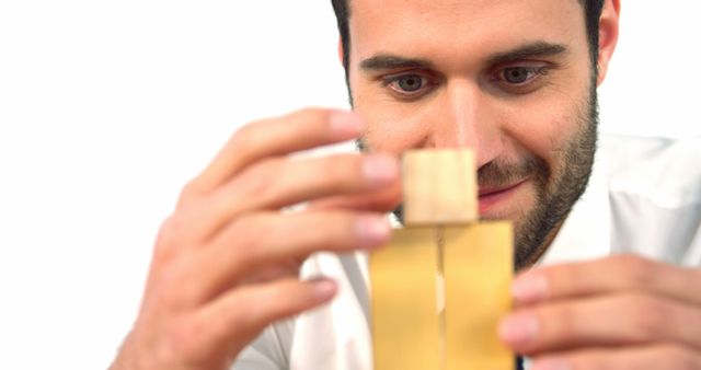 A young Caucasian man is closely examining a bottle of liquid, a perfume or a chemical, with copy space. His focused expression suggests he might be a professional evaluating the product's quality or characteristics.