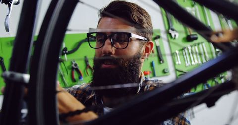 Bearded Mechanic Repairing Bicycle with Focus