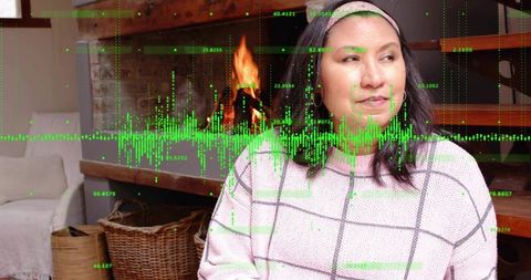 Woman sitting by fireplace wearing checkered knit sweater and headband with green data overlay