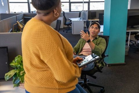 Diverse coworkers collaborating with tablet in modern open-plan office