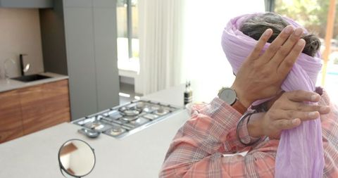 Man tying turban in modern kitchen dinag room reflects tradition