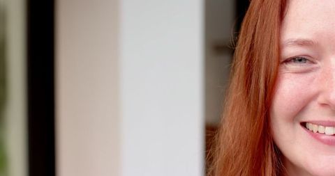 Confident woman smiling with red hair and freckles in modern space