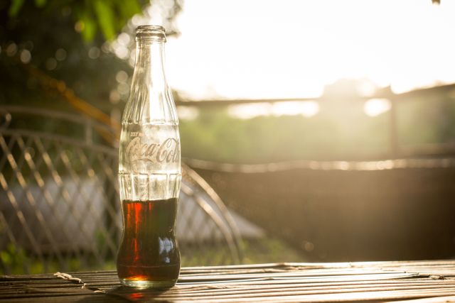 Refreshing Cola Bottle on Wooden Table During Sunset Outdoors - Download Free Stock Images Pikwizard.com