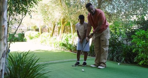 Father Teaching Son Golf on Backyard Green
