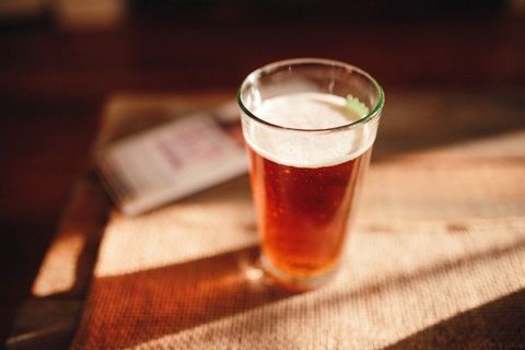 Sunlit Amber Craft Beer Pint on Rustic Wooden Table Closeup with Foam Warm Natural Light Smartphone 