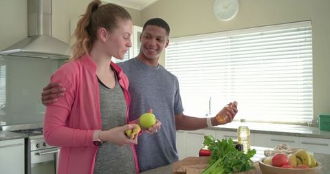 Multiracial couple preparing fresh fruit on modern kitchen island for healthy lifestyle