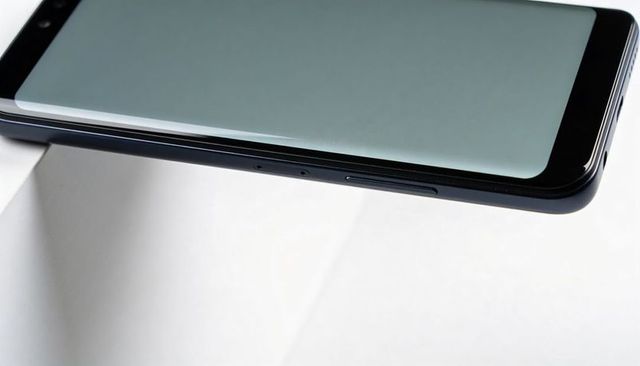 Black smartphone resting on white pedestal showing right-side buttons, holes and bezel