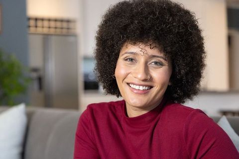 Smiling african american woman relaxing on sofa in cozy modern open-concept living space