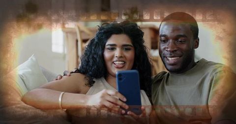 Couple sharing cozy moment on couch while looking at smartphone with film border