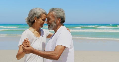 Romantic Senior Couple Dancing on Beach under Clear Blue Sky