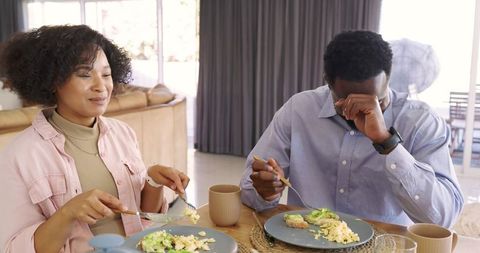 Couple enjoying cozy sunlit breakfast with avocado toast and scrambled eggs
