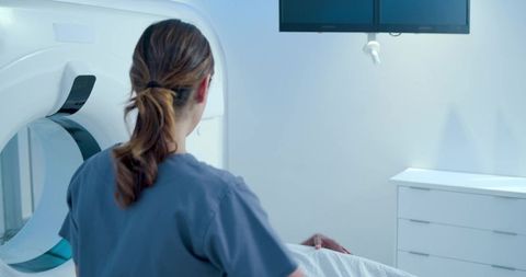 African american technologist positioning patient for ct scan in bright radiology room