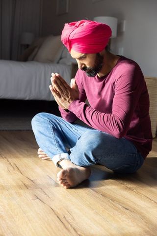 Man Wearing Red Turban Deep in Spiritual Meditation at Home