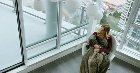 Woman Relaxing with Blanket in Modern High-Rise Apartment