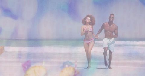 Smiling couple holding hands running on tropical beach