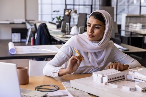Woman in Hijab Analyzing Architectural Model at Workspace