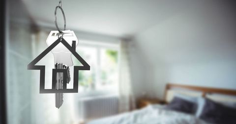 House-shaped keychain with metal key in contemporary bedroom