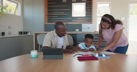 Parents Assisting Young Son with Homework in Modern Kitchen