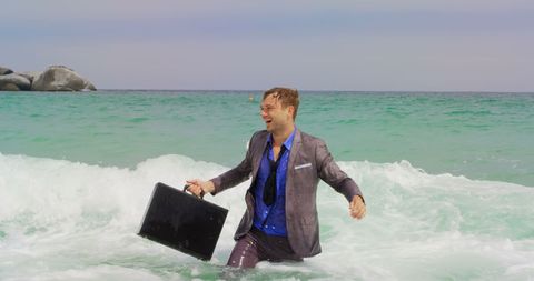 Joyful businessman with briefcase enjoying ocean in suit