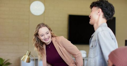 Laughing colleagues sharing light moment during casual modern office meeting