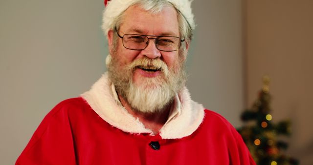 A Caucasian man dressed as Santa Claus smiles warmly, with copy space. His festive costume and cheerful demeanor contribute to the holiday spirit.