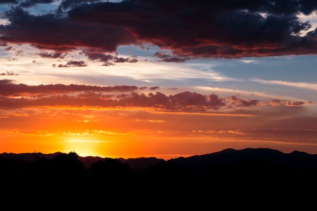 Stunning sunset showcasing vibrant colors in sky with silhouetted mountains in foreground. Perfect for travel websites, nature blogs, or inspirational content. Ideal for promoting outdoor adventures, meditation, or relaxation.