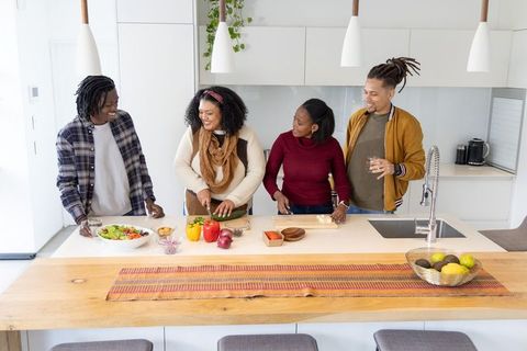 African american friends chopping and preparing meal together on wooden kitchen island