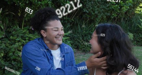 Young couple sharing laughter and affection in garden with floating numeric data overlays