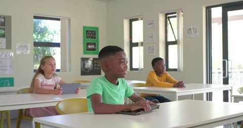 Smiling African American Boy Using Tablet in Bright Modern Classroom