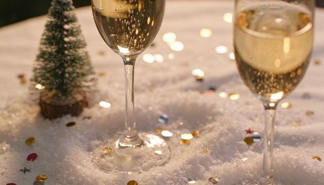 Sparkling champagne flutes nesting in faux snow with confetti and mini pine for holiday cheer