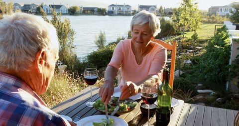 Senior Couple Enjoying Outdoor Meal by Lakeside Setting Sun