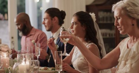 Bride and diverse guests celebrating wedding dinner