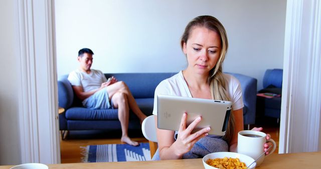 Woman using digital tablet while man using mobile phone at home