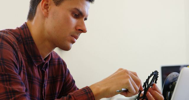 Young man repairing bicycle gear assembly indoors - Download Free Stock Images Pikwizard.com