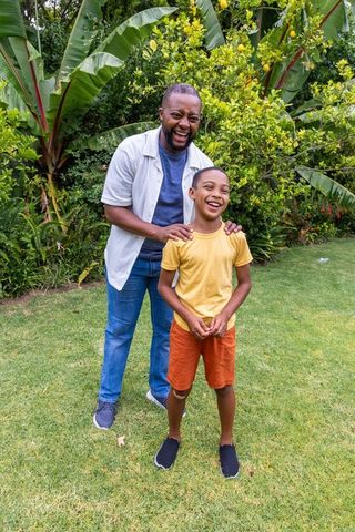African american father and son laughing together in lush garden with citrus tree