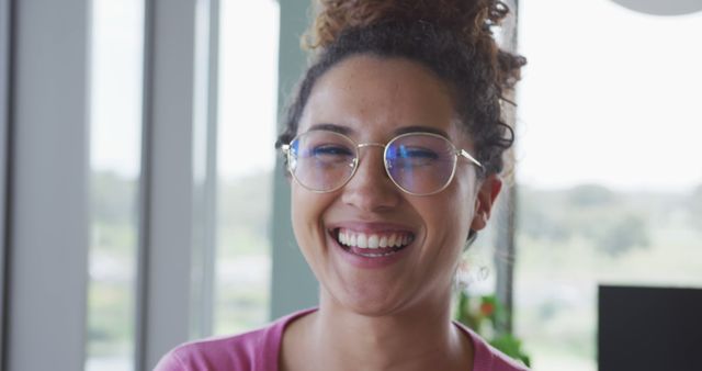 Portrait of smiling biracial creative businesswoman wearing glasses in modern office interior. business and technology in office workplace.