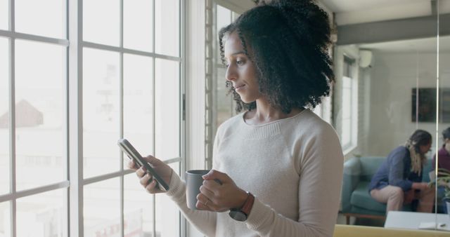 Woman Holding Coffee Cup While Using Smartphone in Bright Room - Download Free Stock Images Pikwizard.com