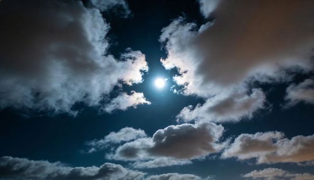 Luminous Full Moon Piercing Cumulus Clouds with Radiant Halo, Dramatic Nocturnal Sky
