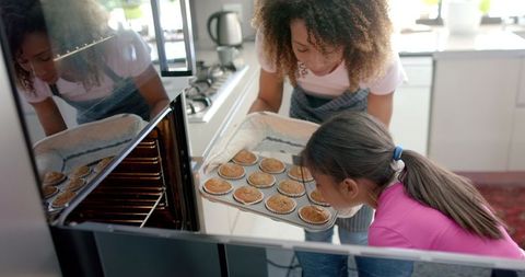 Mother And Daughter Baking Treats Together In Home Kitchen
