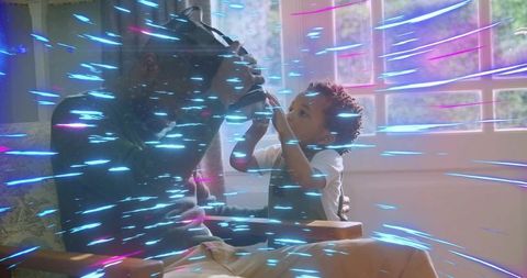 Dad bonding with toddler exploring vr headset in sunlit living room with neon light streaks