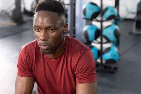 African american athlete resting and focusing between sets in gym with medicine balls