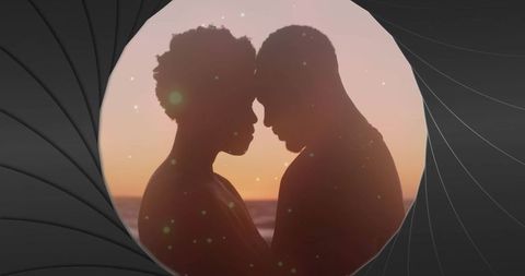 Romantic silhouette of couple at sunset by ocean's edge