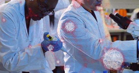 Scientists pipetting at laboratory bench with microscope, teamwork in biotechnology research