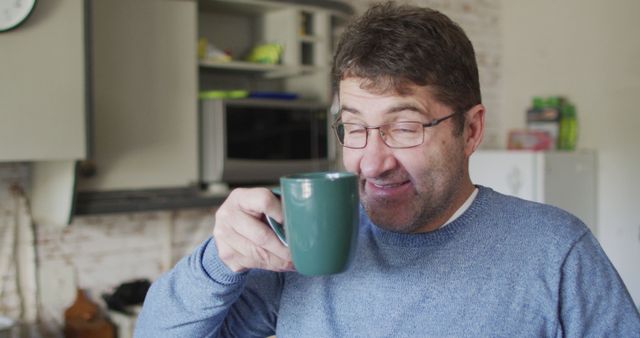 Smiling and relaxed caucasian man drinking coffee in kitchen at home. domestic life and leisure time concept.