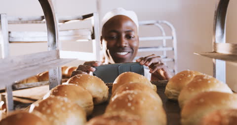 Smiling Baker Capturing Freshly Baked Rolls in Bakery