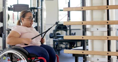 Wheelchair user training with cable row machine in gym for adaptive strength and rehab