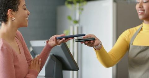 Customer and Cashier Exchanging Phones for Contactless Mobile Payment at Retail Counter